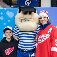 An alumna and her son pose with Louie the Laker at the Detroit Red Wings GVSU Night